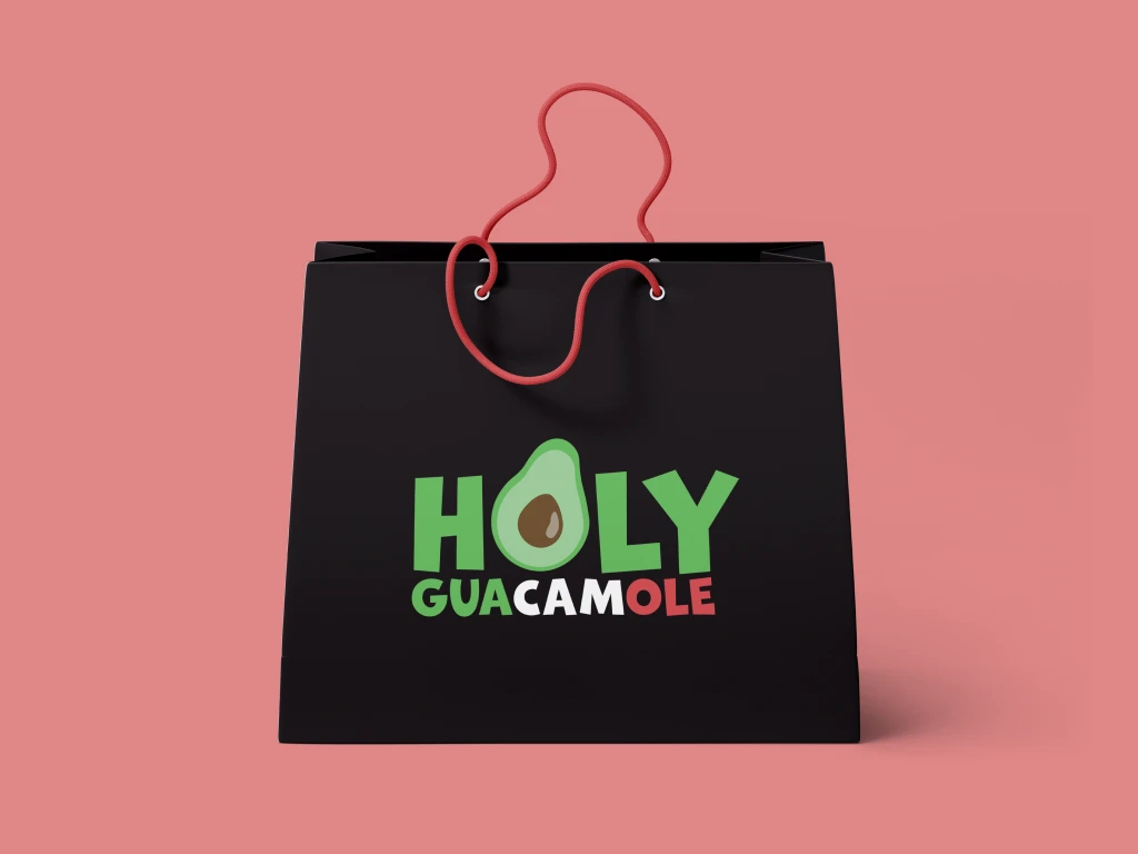 A product mockup featuring the Holy Guacamole's branding. In the middle, a black shopping bag with a large logo of the company. The background is light pink.